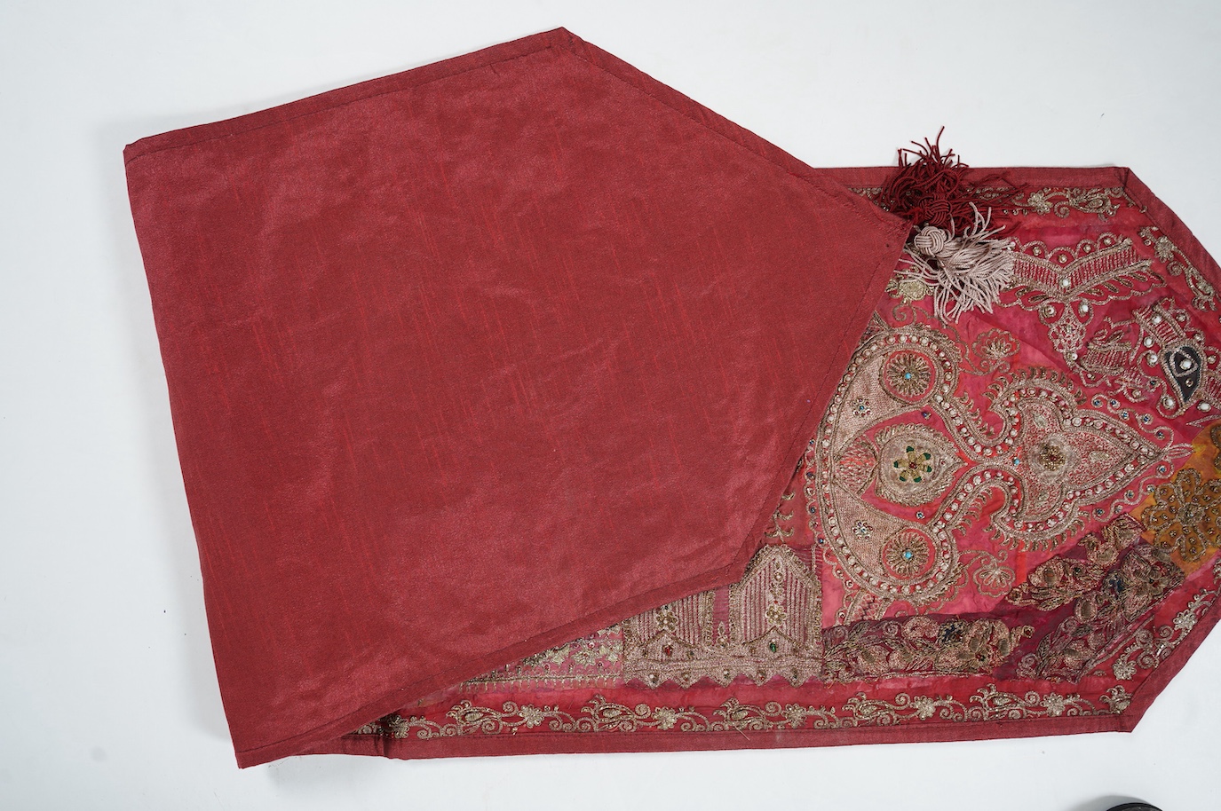 An Indian 20th century red silk marriage banner/hanging, ornately embroidered in silver and gold thread, with raised stump work flowers, corded and designed using simulated pearls and coloured beads etc., 74cm x 43cm. Co